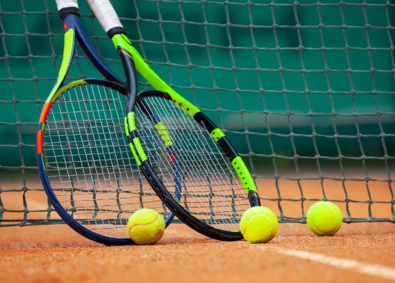 Two tennis rackets and balls leaned against the net.