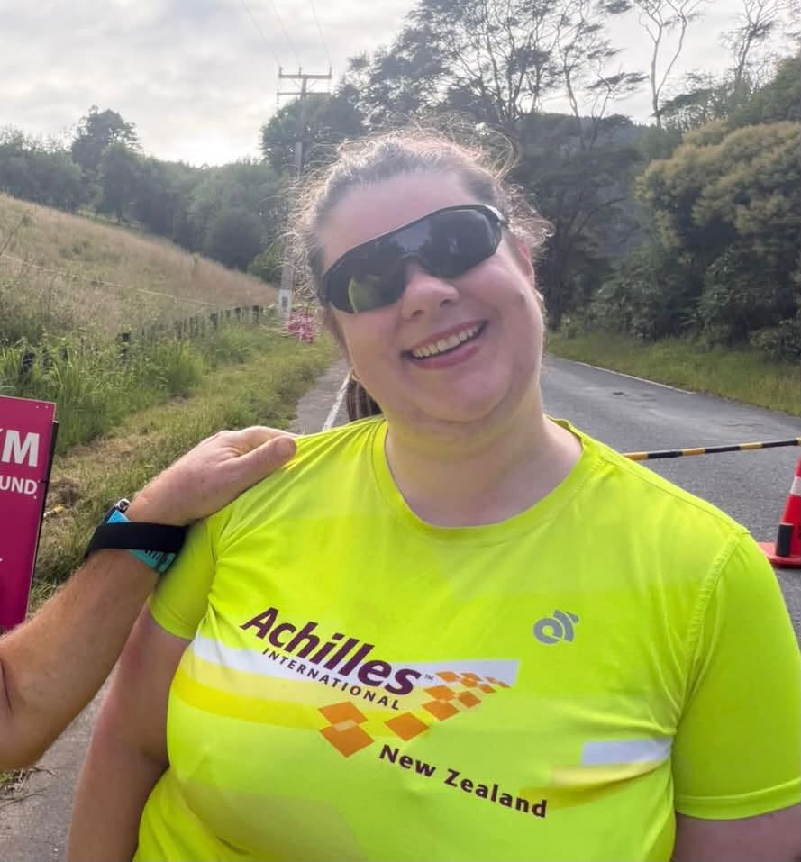 Portrait photo of Mel Jones, Board Member, wearing her Achilles yellow t-shirt and sunglasses