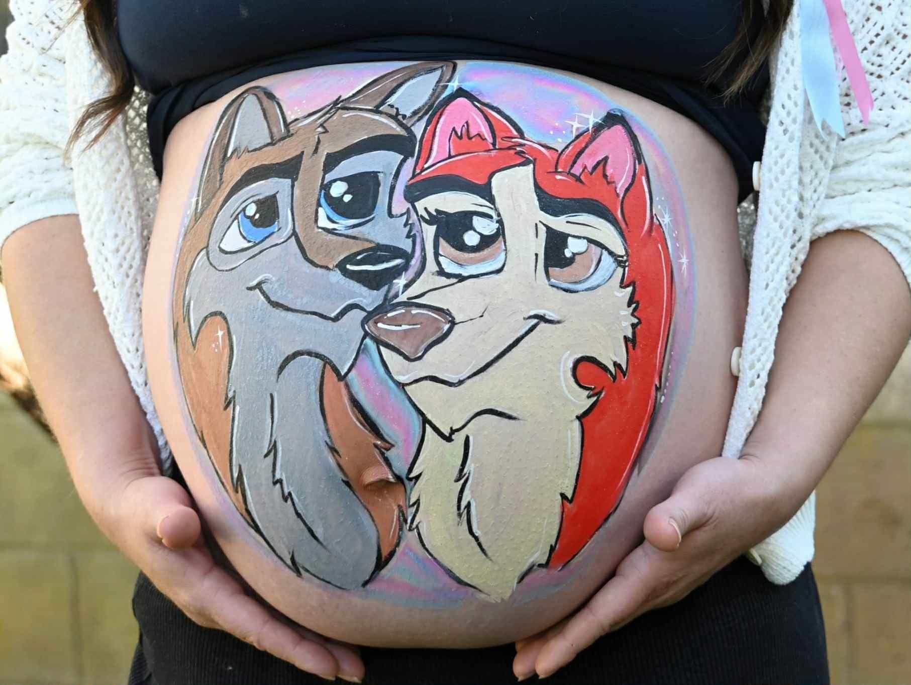 A close up of a baby bump with two smiling foxes painted on it 