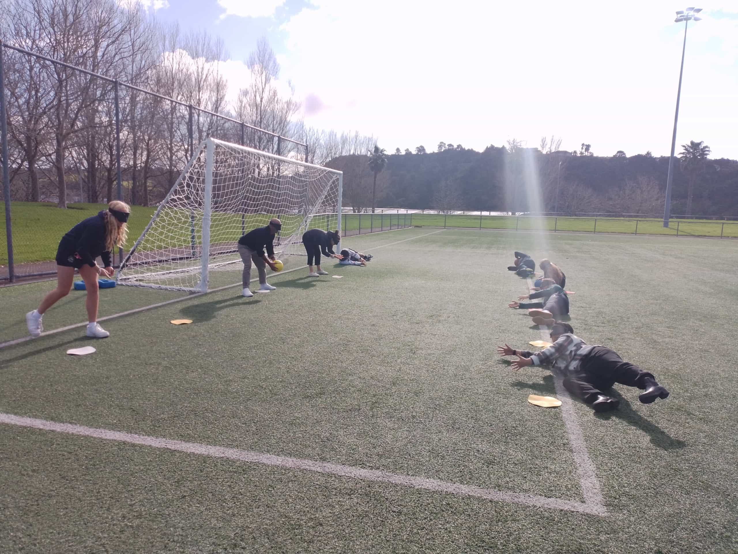 Sun is streaming on outside turf during a Goalball training session for Harbour Sports by Blind Sport NZ