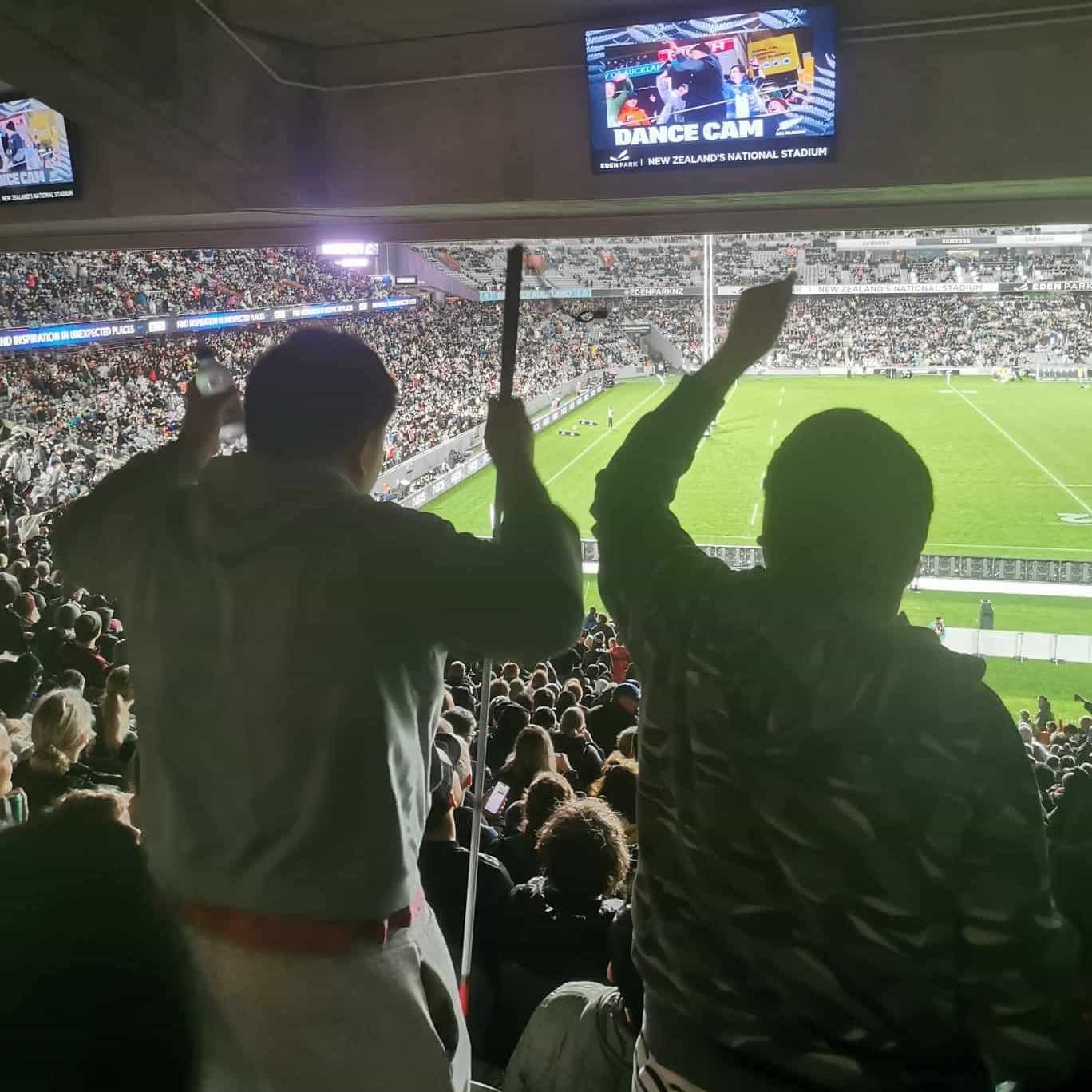 Two people cheer on the all blacks during an audio description session at Eden Park