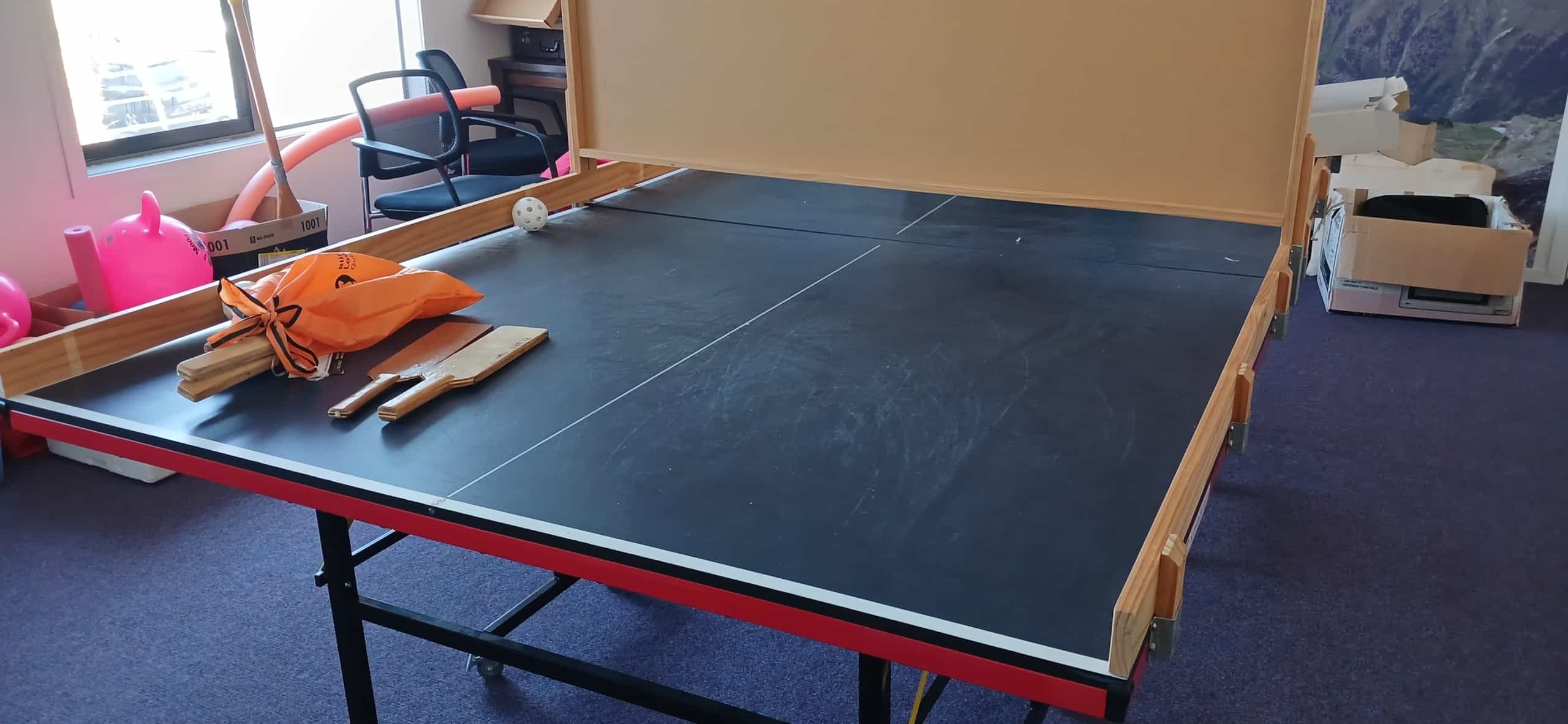 a table tennis table with DIY sides and a centre board adapted for Showdown. The centre board has a gap at the bottom, resting on the side barriers so that there is a gap the ball can go through. 