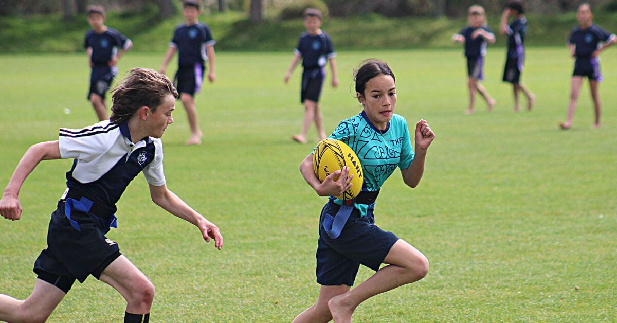Girl running with a rugby ball playing junior rugby in King Country